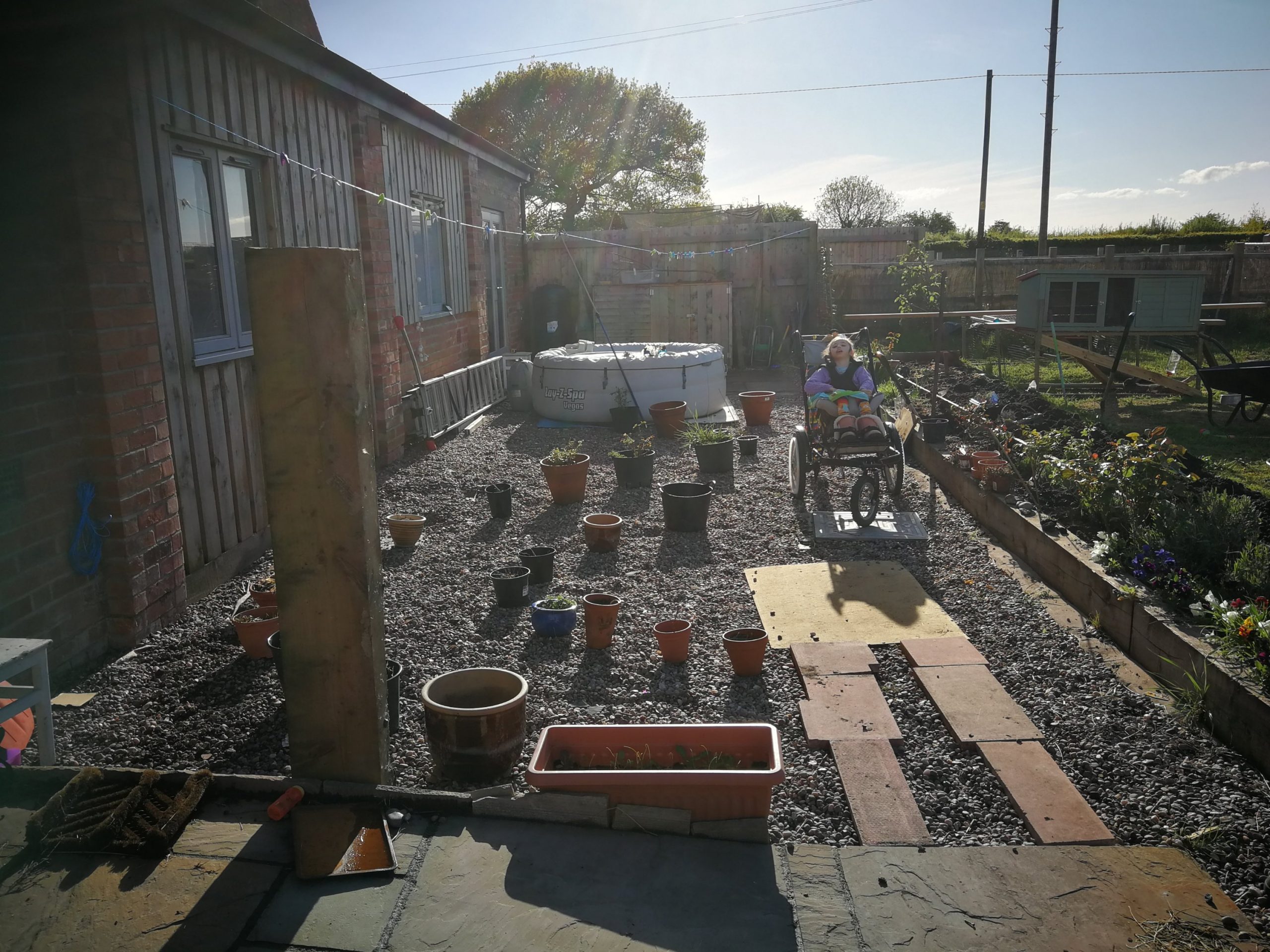 Picture of the space with a path made of pots for edging to get a visual feel for the curves of the path. Willow sitting in the space where the water play table will go.